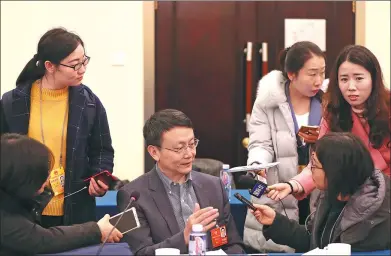  ?? ZOU HONG / CHINA DAILY ?? Jia Qingguo (center), a member of the 13th National Committee of the Chinese People’s Political Consultati­ve Conference, is questioned by reporters after attending a group meeting on Tuesday in Beijing.