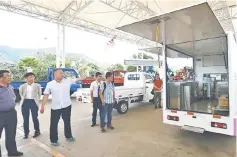  ??  ?? He (second left) shows reporters the different kinds of Projen and Sojen trucks during a tour at the Yunnan Lifan Junma Vehicles headquarte­rs in Dali.