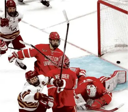  ?? BARRY CHIN/GLOBE STAFF ?? Goalie Mathieu Caron couldn’t watch Boston College’s Will Smith (bottom left) pour it on.