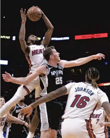  ?? MICHAEL LAUGHLIN/SOUTH FLORIDA SUN SENTINEL ?? The Heat's Derrick Jones Jr. grabs a rebound over the Spurs’ Jakob Poeltl during the first half of their game Wednesday night.
