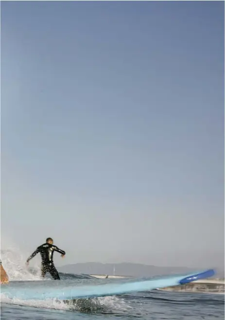  ?? Gabriella Angotti-Jones For The Times ?? CATCHING A WAVE: Jameelah Booker, left, and DeVante Von Deschwaden, below, enjoy a March morning surf session off Marina del Rey. Jessa Williams, at bottom, totes her board at Venice Beach.