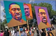  ?? (AP file/Carolyn Kaster) ?? People carry posters with George Floyd’s image on them in August as they march from the Lincoln Memorial to the Martin Luther King Jr. Memorial in Washington.