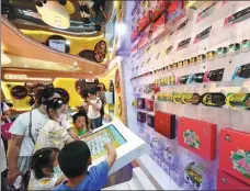  ?? ?? From top: Workers check bottles at a production line of the Wuhan branch of China Resources Snow Breweries in Dongxihu district. Visitors enjoy their day at a food exhibition in Dongxihu.