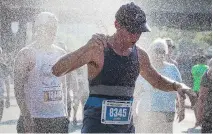  ??  ?? Harry Jurgens cools off under a sprinkler of water after the Vimy Challenge.