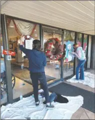  ?? Submitted photo ?? ARTWORK: Ariel Ward, Hot Springs World Class High School
11th-grader, and Mia Brey, HSWCHS art club president and
12th-grader, paint holiday artwork on the windows of the Pines Nursing and Rehabilita­tion Center.