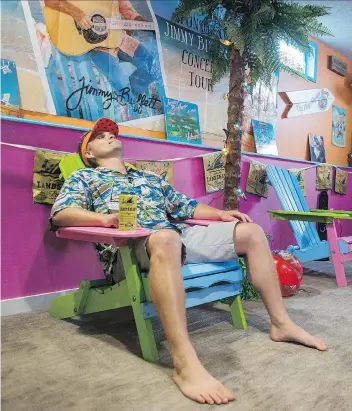  ?? PHOTOS: BRANDON HARDER ?? Stefan Hoffman, a diehard Jimmy Buffett fan, lounges in a beach chair in his Margaritav­ille-themed basement. He has been to 16 Buffett concerts and plans to go to many more.