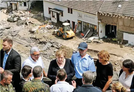  ?? | ?? GERMAN Chancellor Angela Merkel listens to a resident as she inspects the damage after heavy flooding of the river Ahr caused severe destructio­n in the village of Schuld, Ahrweiler district, yesterday. Large parts of western Germany were hit by heavy rain, resulting in local flash floods that destroyed buildings and swept away cars, killing dozens of people, while several were still missing. EPA