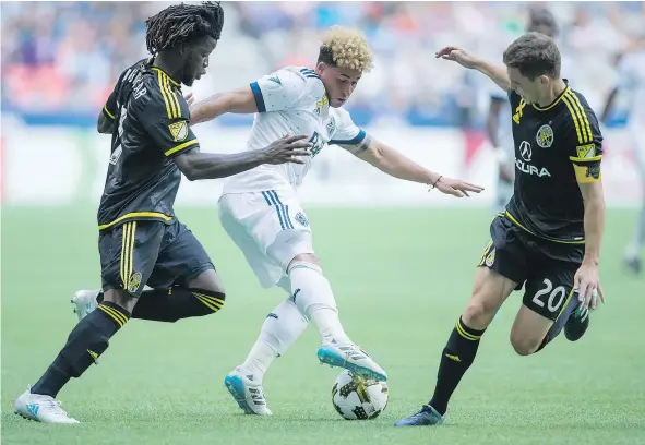  ?? — PHOTOS: CP ?? The Whitecaps’ Erik Hurtado, centre, moves the ball past the Columbus Crew’s Lalas Abubakar, left, and Wil Trapp during their MLS match Saturday at B.C. Place. The teams played to a 2-2 draw, which gave the Caps a one-point edge for first place in the...