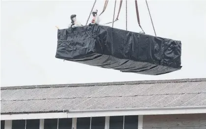  ?? Picture / Mark Mitchell ?? Suited workers remove asbestos from earthquake-damaged Shed 35, at CentrePort, Wellington.