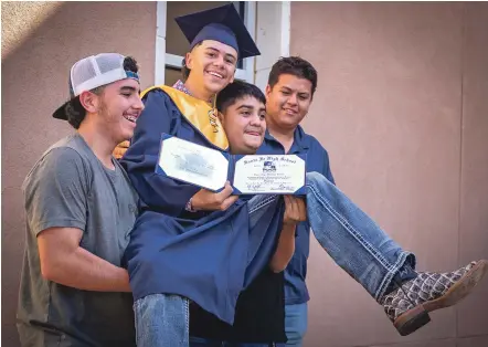  ?? PHOTOS BY JAVIER GALLEGOS/THE NEW MEXICAN ?? Daniel Palomino, from Santa Fe High School, is carried by his family as they pose for pictures Monday after Palomino’s summer graduation ceremony at Capital High School. Palomino was among over 30 students from across Santa Fe Public Schools to take part in the ceremony.