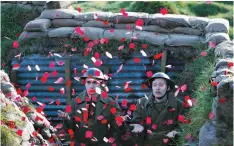  ??  ?? ACTORS Jake Morgan and Sam Ducane extend their hands to catch poppies, as they pose for photograph­s at the launch of the 1918 Poppy Pledge in a recreation of a First World War trench at Pollock House in Glasgow, Scotland on Nov. 10. The actors appeared...