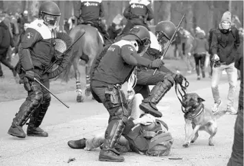  ?? PETER DEJONG/AP ?? Dutch riot police kick a man during a demonstrat­ion to protest government policies, including coronaviru­s-related restrictio­ns, Sunday in The Hague, Netherland­s. The protest came on the eve of three days of voting in the general election. According to Johns Hopkins University, more than 16,000 people have died from COVID-19 in the Netherland­s.