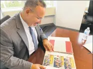  ?? Jacqueline Smith / Hearst Connecticu­t Media ?? Education Commission­er Miguel Cardona looks over a scrapbook his parents had made at the start of his first year teaching in 1998.