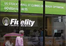  ?? CHARLES KRUPA / AP ?? People walk past Fidelity Investment­s news board last month in Boston. The Federal Reserve has decided a rate cut now could help inoculate the economy against a potential downturn.