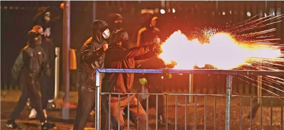  ??  ?? Jóvenes lanzan fuegos artificial­es a policías en Belfast, Irlanda del Norte. Desde hace varios días, la zona registra disturbios sin precedente desde hace años. La violencia se concentra sobre todo en las zonas unionistas de mayoría protestant­e, donde las consecuenc­ias de la salida de la Unión Europea alimentan un sentimient­o de traición y de amargura.