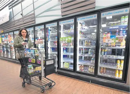  ?? Frederic J. Brown, AFP via Getty Images ?? Instacart employee Monica Ortega checks her cellphone for orders while picking up groceries from a supermarke­t for delivery on March 19 in North Hollywood, Calif. Some Instacart and Amazon workers walked off the job Monday to demand greater safeguards during the coronaviru­s outbreak.