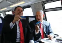  ?? (Courtesy) ?? BENJAMIN NETANYAHU and Transporta­tion Minister Israel Katz show off their Rav-Kav smartcards on the first train to run on the high-speed line from Jerusalem.