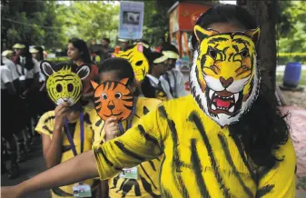  ?? Bikas Das / Associated Press ?? Children wear tiger masks as part of observance­s for Internatio­nal Tiger Day at the Alipore zoo in Kolkata. The tiger is India’s national animal and is categorize­d as endangered.