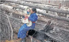  ??  ?? BELOW Ethnic Dukha nomad Jargal Gombosed holds her grandchild outside her family’s reindeer pen.