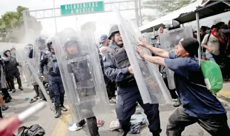  ??  ?? Un centroamer­icano se lanza contra un policía federal, durante la irrupción de la caravana migrante a territorio mexicano.