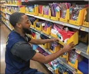  ??  ?? Walmart employee Kevin Treadwell stocks the back-toschool shelves.