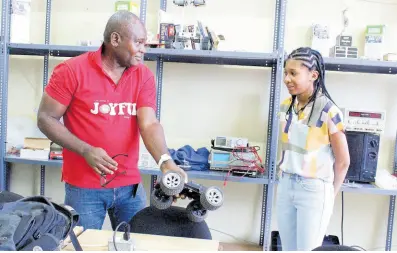  ?? ?? Christophe­r Udeagha, senior lecturer, School of Computing and Informatio­n Technology, shows Jada Wright a prototype inside the Robotics Room during her special orientatio­n and tour of the School of Computing and Informatio­n Technology on January 9. *