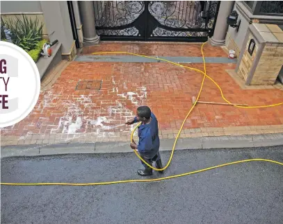  ??  ?? HOSE-DOWN. A man cleans the pavement outside a house in Parktown.