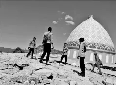  ??  ?? Rescuers and policemen walk on top of a collapsed mosque as they try to find survivors in Pemenang, Lombok.