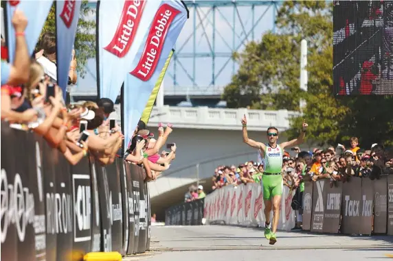  ?? STAFF PHOTOS BY DAN HENRY ?? Marino Vanhoenack­er from Jabbeke, Belgium, raises his hands in victory as he wins the 2016 Little Debbie Ironman Chattanoog­a triathlon on Sunday. Vanhoenack­er won overall with a time of 8:12:22. More than 2,700 athletes registered to compete in a...