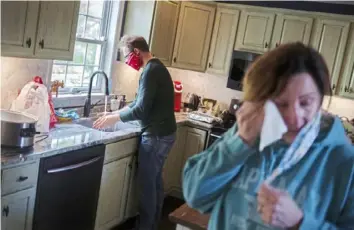  ?? Joseph Ressler ?? “The masks are good at soaking up the tears” is the title of this photo by Joseph Ressler of Dauphin County, quoting Janet Allen. Behind Janet is her husband, Paul Allen, who washes his hands while she dries her tears immediatel­y after a veterinari­an came to their home in Strasburg to euthanize their elderly dog on April 13, 2020.