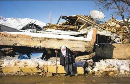  ?? Francisco Seco Associated Press ?? ZEHRA KURUKAFA walks past a home in the village of Polat, Turkey, that was destroyed by the magnitude 7.8 earthquake of Feb. 6.