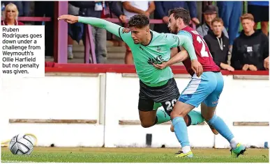  ??  ?? Ruben Rodrigues goes down under a challenge from Weymouth’s Ollie Harfield but no penalty was given.