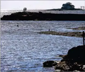  ?? PETER HVIZDAK - NEW HAVEN REGISTER ?? Two people take in a view of the Thimble Islands and Long Island Sound from a jetty near the Owenego Inn, Beach and Tennis Club in Branford.