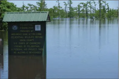  ?? Photos contribute­d by Linda Newbury ?? Waters on the rise: Above, a sign placed on the Felsenthal Wildlife Refuge shows how high the water levels are in Felsenthal. Below, the river dock at Felsenthal is flooded due to elevated water levels.