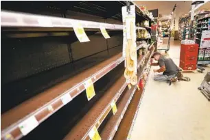  ?? U-T FILE ?? Jose Nunez, a grocery clerk at the Ralphs supermarke­t in the La Jolla Square shopping center, stocks empty shelves early in the morning on March 19.