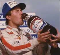  ?? PHOTO COURTESY OF TIM MILLER ?? Alan Kulwicki, winner of the 1984 Molson 200, celebrates with the custom-made beer bottle and its contents, while 2013’s Indy 500 winner, Tony Kanaan, enjoys the customary drink of milk.