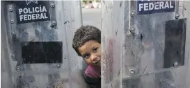  ?? RODRIGO ABD, THE ASSOCIATED PRESS ?? Elias López, a three-year-old Honduran migrant, plays between the shields of a line of Mexican riot police in Tijuana, Mexico.