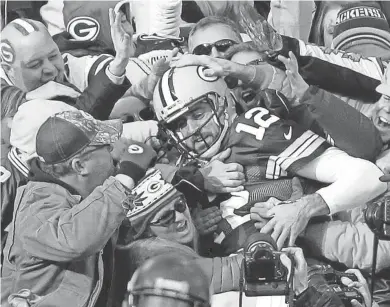  ?? RICK WOOD / MILWAUKEE JOURNAL SENTINEL ?? Green Bay Packers quarterbac­k Aaron Rodgers is swarmed by fans after scoring a touchdown and performing a Lambeau Leap.