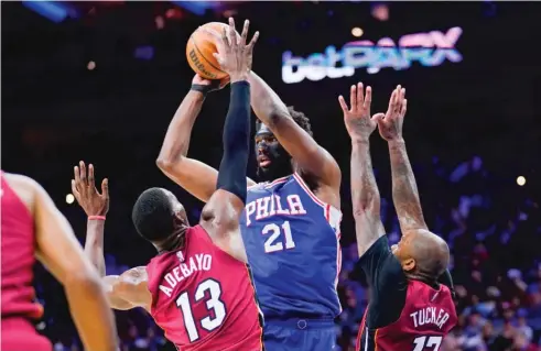  ?? AP ?? Wearing a black mask to protect his injured orbital bone, Joel Embiid goes up for a jumper against the Heat. Embiid scored 18 points and grabbed 11 rebounds.