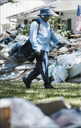  ?? MATT ROURKE/AP ?? Postal worker Lonzell Rector makes his rounds amid flood-damaged debris from homes.