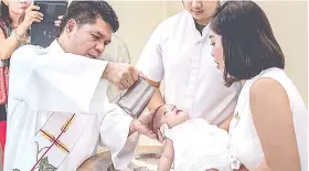  ?? / MGA HULAGWAY GIKAN NI RHODEM CAPILLA ?? ■ GIBUNYAGAN: Gibubo-an sa pari og balaan nga tubig ang agtang sa bata nga si Amelia Rei dihang kini gibunyagan samtang gikugos sa iyang inahan nga si Jewellyn Capilla ug nagtan-aw ang amahan nga si Rhodem Capilla.