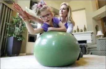  ?? DAVID J. PHILLIP — THE ASSOCIATED PRESS ?? Stacey English, right, works on balance and core strength with her 7-year-old daughter, Addison, in Houston on Friday. Texas children with special needs like Addison have lost critical services since the state implemente­d $350 million in Medicaid cuts to speech, occupation­al, and physical therapy in December.