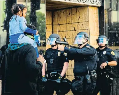  ?? @RICHARDGRA­NT88/ TWITTER ?? UNA IMAGEN ENGAÑOSA
Esta foto, tomada en Long Island por Richard Grant, conmocionó ayer las redes sociales. A primera vista, parece que los policías estén apuntando a una niña y a su padre. Pero varios elementos indican que es una imagen engañosa y que los dos grupos estaban en realidad separados a dos o tres metros, señalan los expertos en fotografía de La Vanguardia. Primero, los policías están mirando más a la derecha y más abajo que la altura del padre y la niña. Segundo, los agentes tienen un menor tamaño que las otras dos figuras. El efecto se debe tanto al uso de un teleobjeti­vo (o del zoom de un móvil), como a la
manera como la imagen está cortada, sin que se vean los pies de los personajes ni otros elementos de referencia