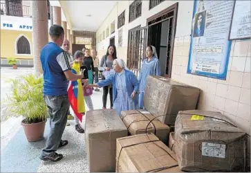  ?? Miguel Gutierrez For The Times ?? SISTER Ana Medina Suarez, second from right, takes delivery of a shipment of food and clothing sent by Tere Caicedo in Los Angeles. Suarez runs a retirement home for low-income men in southwest Caracas, Venezuela.