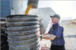  ?? Nati Harnik ?? The Associated Press Farmer Don Bloss checks an auger transferri­ng corn Thursday on his farm in Pawnee City, Neb. Some of his neighbors have quit farming becuase it is no longer financiall­y viable for them.