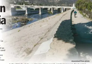  ?? Associated Press photo ?? In this 2016 file photo, a cyclist rides along recently installed temporary flood control walls along the low level L.A. River in Los Angeles. California water managers will vote Tuesday whether to reinstate some water restrictio­ns and conservati­on...