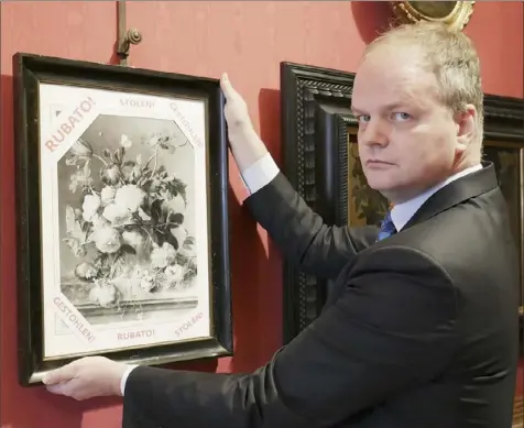  ?? Uffizi press office via The New York Times ?? A photo provided by the Uffizi press office of Eike Schmidt, director of the Uffizi Galleries in Florence, Italy, hanging a black-andwhite copy of “Vase of Flowers,” by the Dutch painter Jan van Huysum with the word “stolen” in different languages. The Uffizi Galleries is calling on the German government to step into a dispute over the Baroque painting that German soldiers took 75 years ago.