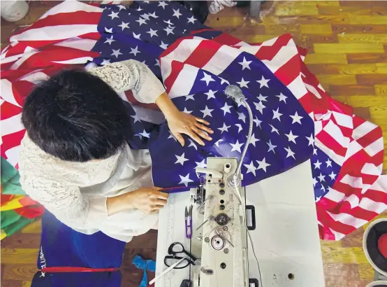  ?? AFP ?? As the US-China trade war rages, a factory set amid corn and mulberry fields in central China stitches together US and ‘Trump 2020’ flags — and business is good.