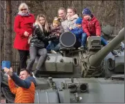  ??  ?? A family takes a photo Wednesday sitting atop a T-55M Soviet tank installed as a monument in Kirovsk, east of St. Petersburg, Russia.
(AP/Dmitri Lovetsky)