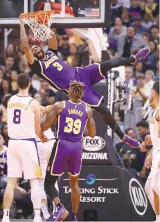  ?? — USA Today Sports ?? Los Angeles Lakers forward Anthony Davis (3) reacts as he hangs from the rim after a slam dunk against the Phoenix Suns.